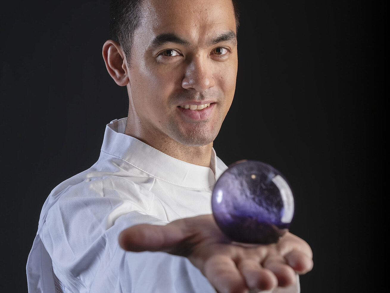Chef Pâtissier Taro Bünemann in der Orangerie im Maritim Hotel Timmendorfer Strand, hält eine violette Kugel in der Hand.