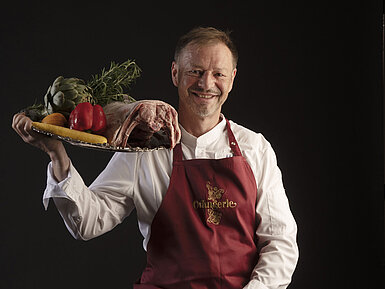 Küchenchef Thomas Lemke trägt ein Tablett mit Gemüse und Fleisch in der Orangerie im Maritim Hotel Timmendorfer Strand.