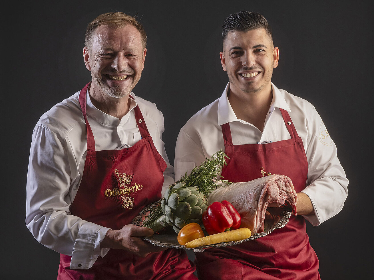 Küchenchefs Simone Melis und Thomas Lemke präsentieren ein Tablett mit Gemüse und Fleisch in der Orangerie des Maritim Hotels