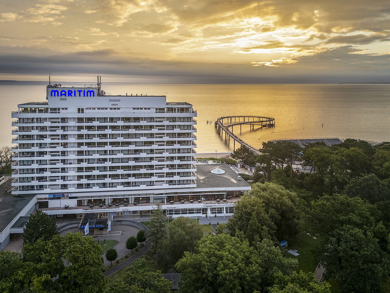 Maritim Seehotel Timmendorfer Strand bei Sonnenaufgang mit Seebrücke und Meerblick.
