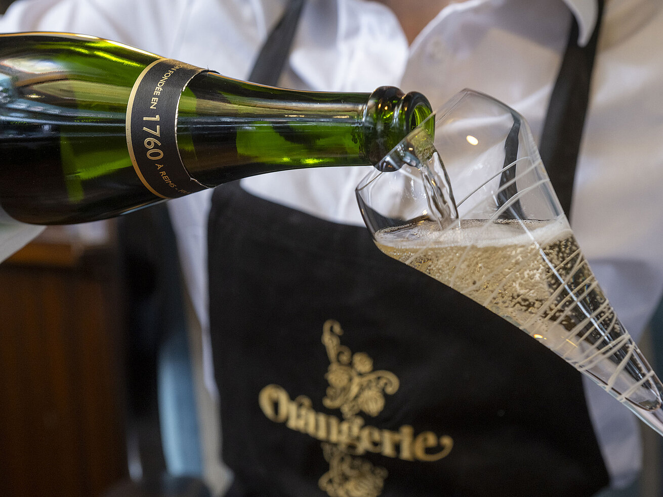 Champagner wird in ein Glas im Restaurant Orangerie im Maritim Timmendorfer Strand eingeschenkt.