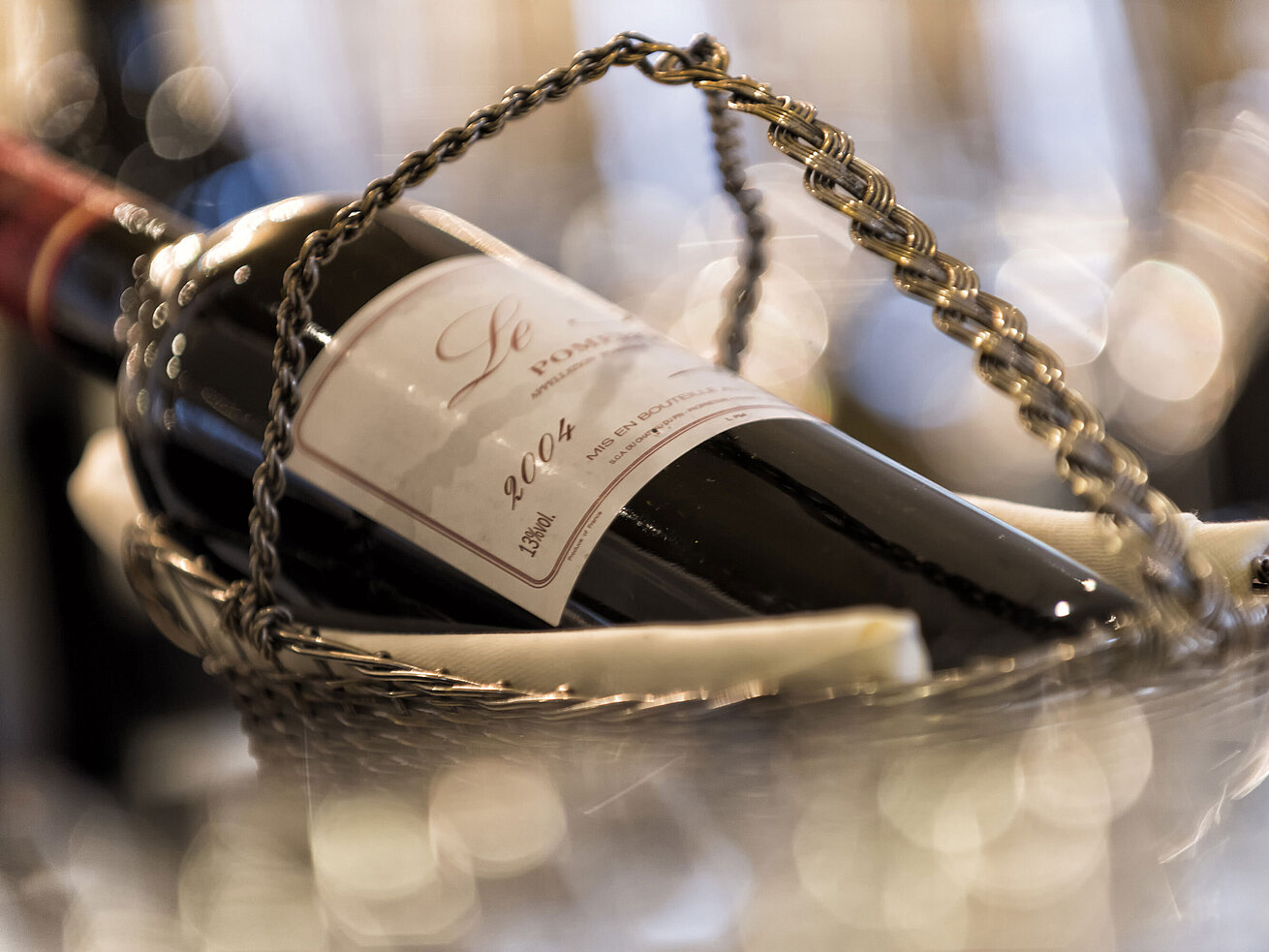  Flasche Rotwein aus dem Jahr 2004 in einem silbernen Weinkorb in der Orangerie.