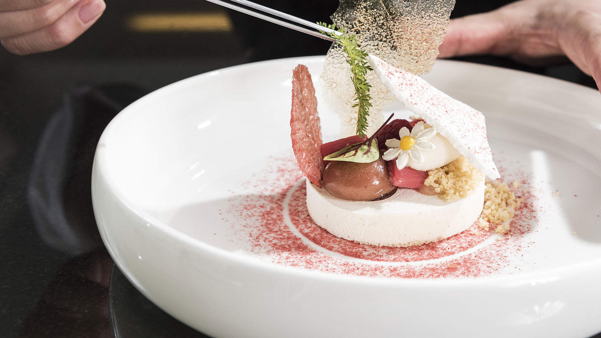 Dessertkunstwerk mit Sorbet, Creme und filigraner Dekoration auf weißem Teller in der Orangerie.