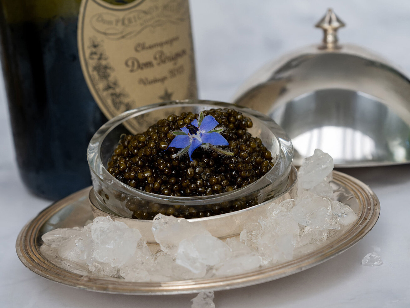 Feiner Kaviar stilvoll serviert auf Eis mit Silberhaube im Sternerestaurant Orangerie.