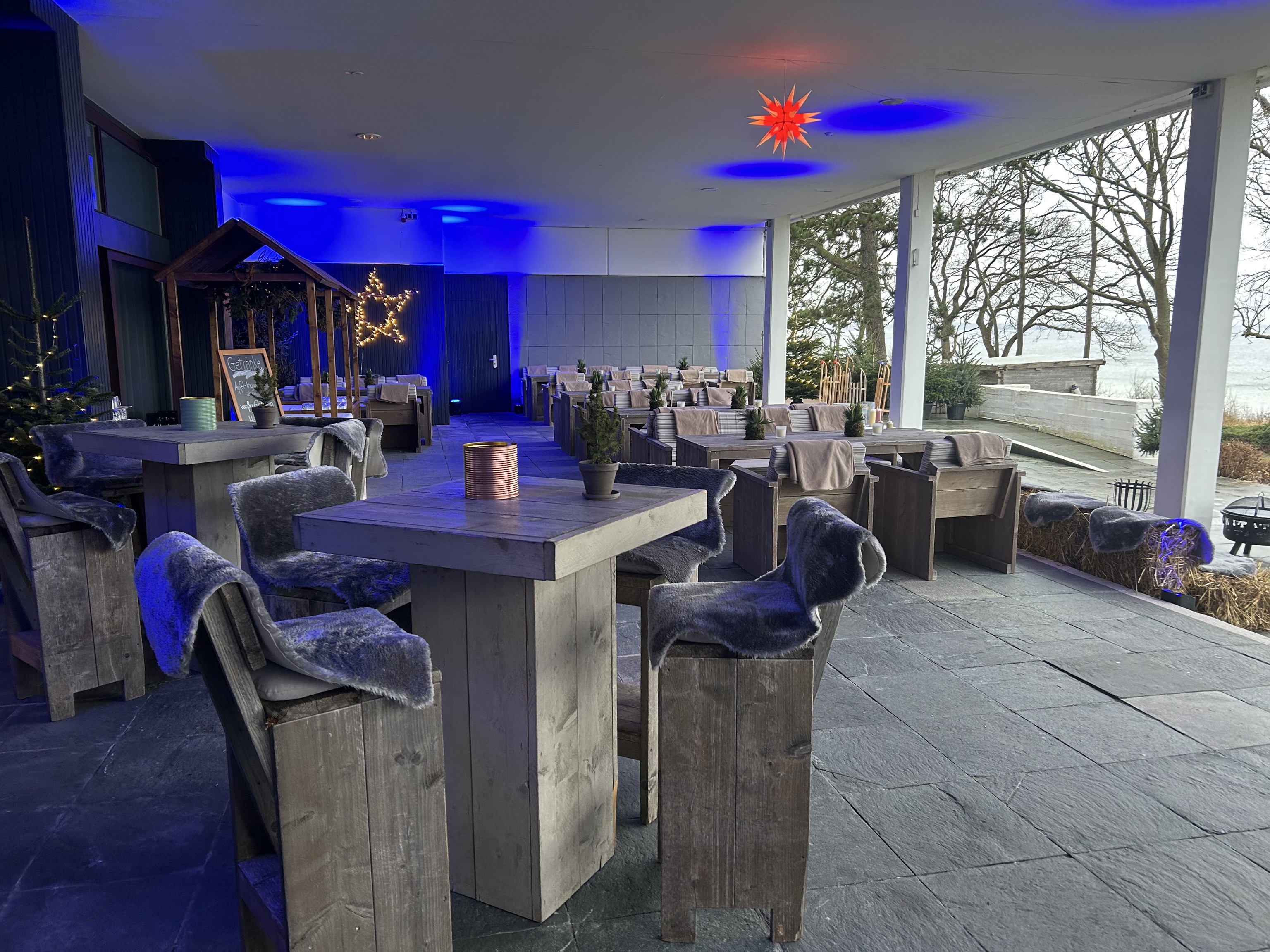 Winterzauber Terrasse mit rustikalen Holztischen, Fellen und Blick auf die Ostsee im Maritim Hotel.